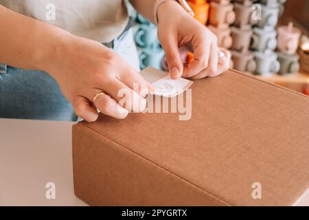 Photos recadrées mains de femme d'affaires emballage, préparant le colis pour le paquet de livraison à l'acheteur. Purshase de vaisselle pour bébé en silicone Banque D'Images