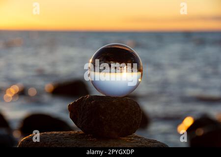 La boule de verre se trouve sur la pierre supérieure reflétant la plage et la mer Banque D'Images