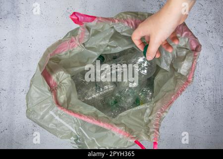 Mettez les bouteilles en plastique à la main dans un sac poubelle prêt à être recyclé, à gérer les déchets et à recycler le plastique. Tri des bouteilles de déchets en plastique, vue de dessus Banque D'Images