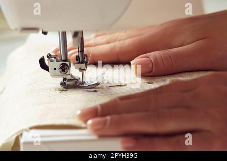 Les mains de couturière féminine recadrées mettant le textile blanc doux en tissu avec le motif de couture de contour de point sur la machine à coudre Banque D'Images