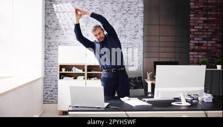 Bras exercice d'étirement debout près du bureau Banque D'Images