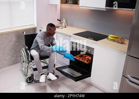 Homme handicapé utilisant le four à micro-ondes pour la cuisson Banque D'Images