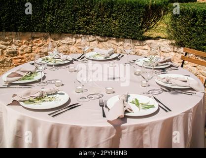 Belle décoration de mariage en plein air en ville. Bougies et fleurs séchées et accessoires avec bouquets et verres sur la table avec nappe en lin sur la table Newlywed sur la pelouse verte Banque D'Images