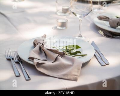 Belle décoration de mariage en plein air en ville. Bougies et fleurs séchées et accessoires avec bouquets et verres sur la table avec nappe en lin sur la table Newlywed sur la pelouse verte Banque D'Images