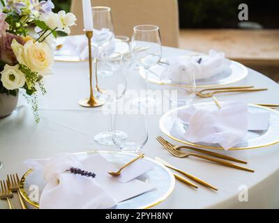 Belle décoration de mariage en plein air en ville. Bougies et fleurs séchées et accessoires avec bouquets et verres sur la table avec nappe en lin sur la table Newlywed sur la pelouse verte Banque D'Images