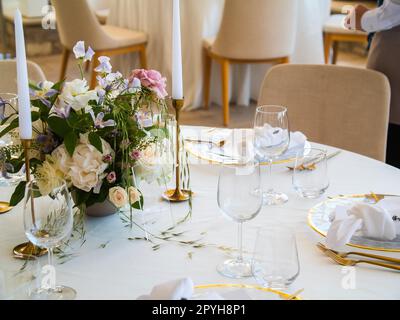 Belle décoration de mariage en plein air en ville. Bougies et fleurs séchées et accessoires avec bouquets et verres sur la table avec nappe en lin sur la table Newlywed sur la pelouse verte Banque D'Images