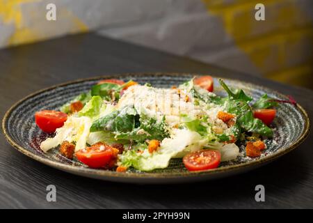 Salade César dans une assiette d'argile sombre sur une table en bois Banque D'Images