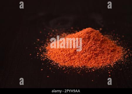 Un tas de poudre de piment rouge sur une surface en bois noir. Espace de copie Banque D'Images