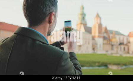 Man prend des photos sur son téléphone portable dans la vieille ville. Vue arrière Banque D'Images