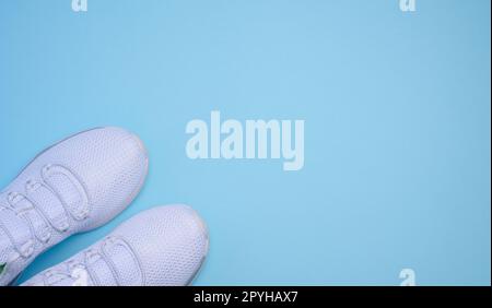 Baskets en tissu blanc sur fond bleu, vue du dessus Banque D'Images