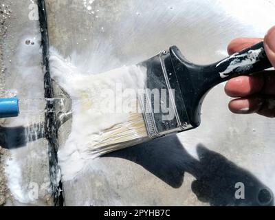 Gros plan sur les mains d'un artisan lavant une brosse de nettoyage après le travail de peinture terminé Banque D'Images