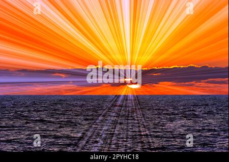 Un coucher de soleil sur l'océan avec des rayons du soleil émanant de l'arrière des nuages Banque D'Images