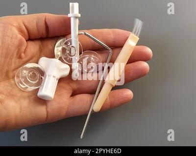 Bobines en plastique transparent d'une machine à coudre moderne dans la paume d'une femme - couturières, aiguilles, enrouleur de fil, outil de fouettage. Fond gris. machines à coudre Banque D'Images