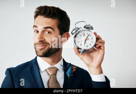 C'est à nouveau cette fois-ci. Photo studio d'un jeune marié élégant tenant une horloge sur fond gris. Banque D'Images