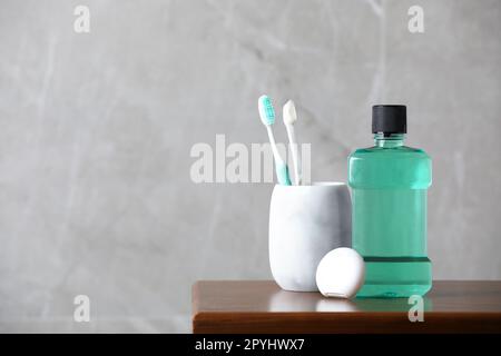 Bouteille de rince-bouche, brosses à dents et fil dentaire sur table en bois, espace pour le texte Banque D'Images