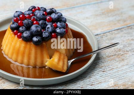 Délicieux pudding au caramel, aux myrtilles et aux groseilles sur une table en bois Banque D'Images