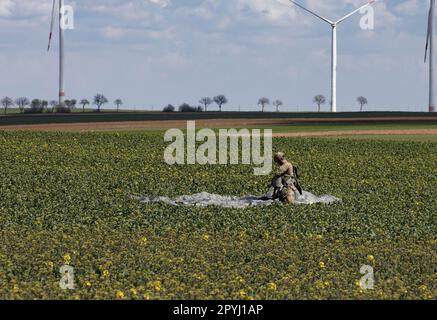 Un parachutiste récupère son parachute après avoir atterri dans un champ après avoir sauté d'un C-130J Super Hercules lors d'un saut d'entraînement aéroporté sur 14 avril 2023 près d'Alzey, en Allemagne. Les forces d'opérations spéciales en Europe effectuent régulièrement et rigoureusement des entraînements aéroportés pour assurer la maîtrise continue de leurs cavaliers et de leurs maîtres-macareux et pour montrer au peuple américain, à ses alliés, à ses partenaires et à ses adversaires que les SOF sont présents, létaux et prêts à rapidement et efficacement n'importe quel adversaire n'importe où et n'importe quand. (Photo des États-Unis Le sergent d'état-major de l'armée Nicholas Moyte) Banque D'Images