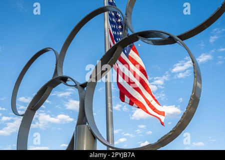 Le drapeau des États-Unis se faisant passer derrière les anneaux olympiques au parc olympique du lac Lanier, un lieu de compétition olympique d'aviron et de canoë/kayak, à Gainesville, en Géorgie. Banque D'Images