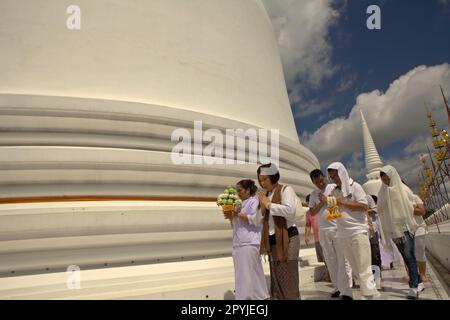 Un groupe de pèlerins priant en train de faire le tour d'un stupa géant blanc au Wat Phra Mahathe Woramahawihan, le principal stupa bouddhiste de Nakhon si Thammarat, la plus grande province du sud de la Thaïlande. Banque D'Images