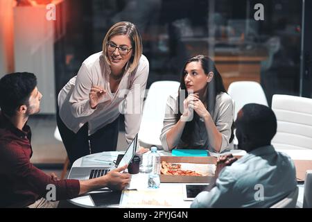 En prenant leur dévouement tout au long de la nuit. collègues ayant une réunion tard dans la nuit dans un bureau moderne. Banque D'Images