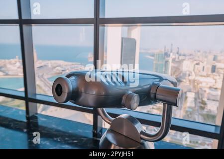 Télescope optique touristique sur le point de vue de la terrasse d'observation surplombant la ville d'Abu Dhabi pendant un coucher de soleil coloré aux Émirats Arabes Unis Banque D'Images