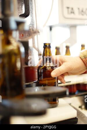 Mains, bière et bouteille dans l'usine, la brasserie ou l'usine de fabrication pour l'inspection de la qualité. Alcool, chaîne de production et personne de prendre le verre Banque D'Images