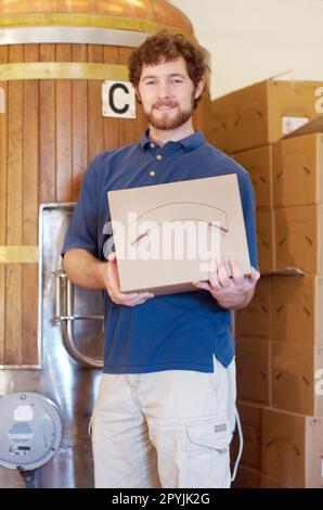 Boîte, brasseur et portrait d'homme avec caisse à bière après avoir fabriqué le produit dans une usine ou une distillerie. Industrie, heureux et jeune homme, travailleur Banque D'Images