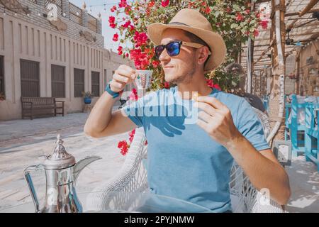 Lorsqu'il est assis dans un café traditionnel des Émirats arabes Unis, l'homme se mêle de café arabe parfumé et de grignoter des dattes douces, se baignant dans la riche culture et le salut Banque D'Images