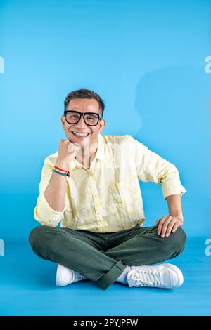 Homme à lunettes et une chemise portant un bracelet arc-en-ciel sur un fond coloré Banque D'Images