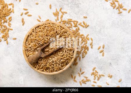 Bol de grain de seigle sec cru avec une cuillère en bois sur la vue de dessus de table blanche Banque D'Images