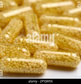 Capsules médicales transparentes avec granules jaunes à l'intérieur sur fond blanc, comprimés pour le traitement, vitamines Banque D'Images