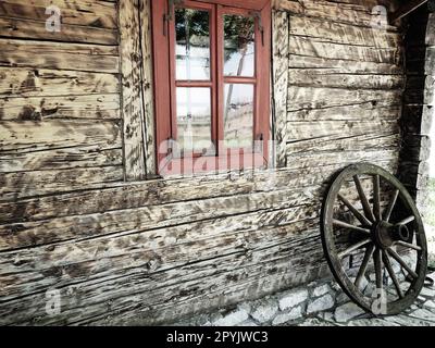 Stanisici, Bijelina, Bosnie-Herzégovine, 25 avril 2021. Ferme de village en rondins. Habitation traditionnelle de montagne bosniaque du 19e siècle. Bâtiment ethno restauré. Roue en bois antique de char Banque D'Images