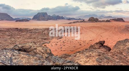 Paysage rocheux dans le désert de Wadi Rum le matin, petites tentes de camp visibles à distance Banque D'Images