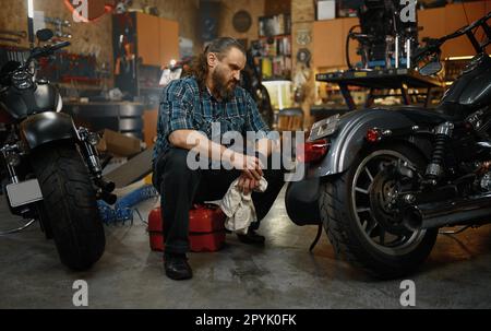 Homme mûr barbu moto de nettoyage dans le poste de travail de garage Banque D'Images