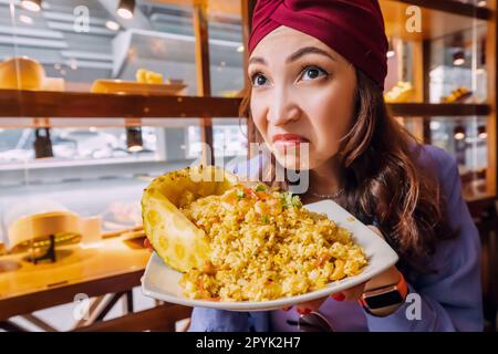 Une femme insatisfaite cliente du restaurant thaïlandais a l'odeur dégoûtante d'un plat de riz à l'ananas avec des ingrédients gâtés et va se faire plaisir Banque D'Images