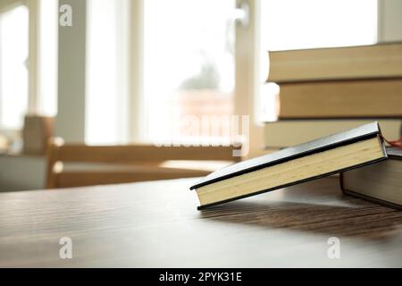 Concept d'apprentissage de l'éducation avec le livre d'ouverture ou manuel à la maison dans la salle de bureau, piles empilées d'archives académiques de texte de littérature sur le bureau de lecture et allée d'étagères dans l'intérieur de fond de salle de classe d'étude d'école Banque D'Images