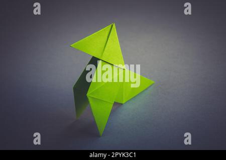 L'origami en papier vert est isolé sur un fond gris Banque D'Images