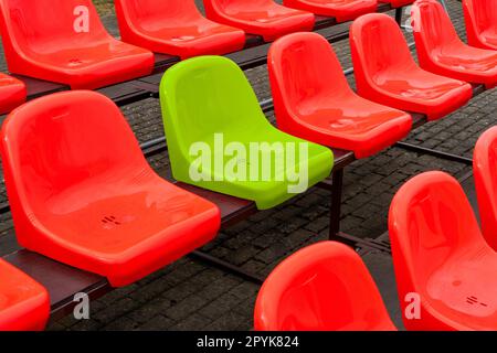 Un siège vert parmi les sièges de couleur rouge dans un stade Banque D'Images