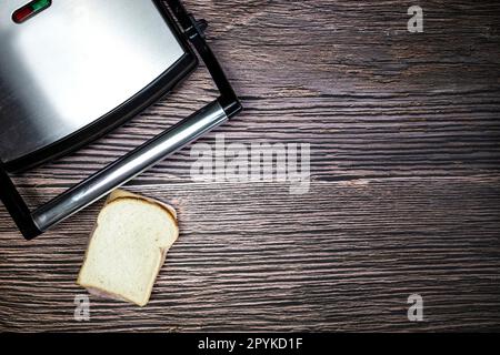 Gril moderne avec sandwich au fromage grillé sur une table en bois, vue sur l'espace de copie Banque D'Images