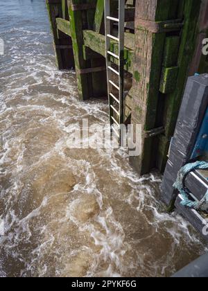 L'eau tourbillonnante d'une rivière sur une jetée avec un escalier en fer qui mène dans l'eau Banque D'Images