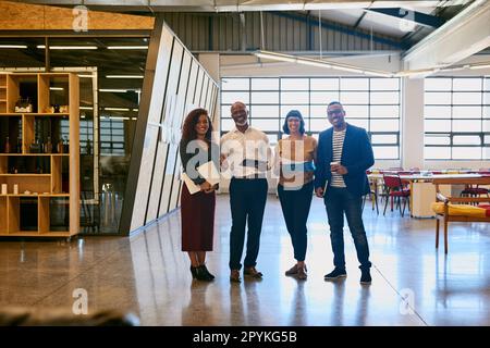 Nous comptons sur le travail d'équipe pour réussir. Portrait d'un groupe de designers se posant ensemble dans leur bureau. Banque D'Images