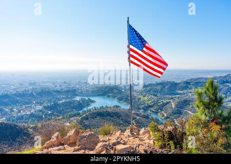 Drapeau américain ordonnant fièrement le sommet de Griffith Park Trail et donnant sur la vue imprenable sur la ville et les montagnes environnantes. Banque D'Images