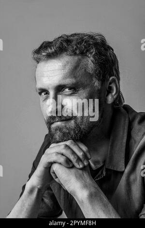 Mignon et beau homme caucasien posant en studio photo avec les mains ensemble. Photo en noir et blanc, avec fond blanc, ce qui en fait un complément polyvalent et intemporel à n'importe quel projet. Photo de haute qualité Banque D'Images