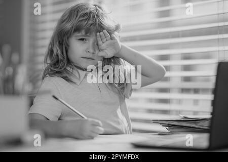 Fatigué triste garçon d'école en faisant des devoirs. Enfant tenir un crayon et dessiner à la maison. Un jeune garçon qui dessine à la table. Banque D'Images