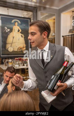 un garçon en uniforme sert du vin pendant une fête, un événement festif ou un mariage à l'intérieur Banque D'Images