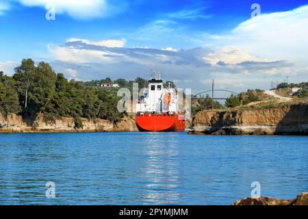 Un cargo navigue entre les rochers du canal de Corinthe. Paysage estival pittoresque du canal de Corinthe dans une journée ensoleillée et lumineuse contre un ciel bleu avec wh Banque D'Images