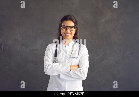 Portrait d'une femme souriante et confiante sur fond de béton gris. Banque D'Images