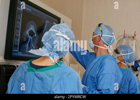 S'assurer que son personnel est sur la même page chirurgicale. une équipe de chirurgiens discutant des examens médicaux d'un patient pendant la chirurgie. Banque D'Images