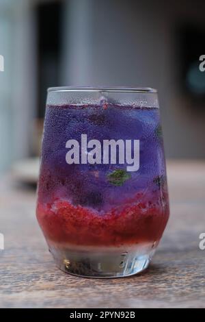 Cliché vertical d'une boisson fraîche à base de fruits aux fraises et thé bleu à base de Clitoria Ternatea, généralement connue sous le nom de fleur de pois aux papillons sur un bon Banque D'Images