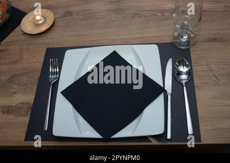Une plaque blanche classique sur une table en bois avec du papier de soie noir Banque D'Images